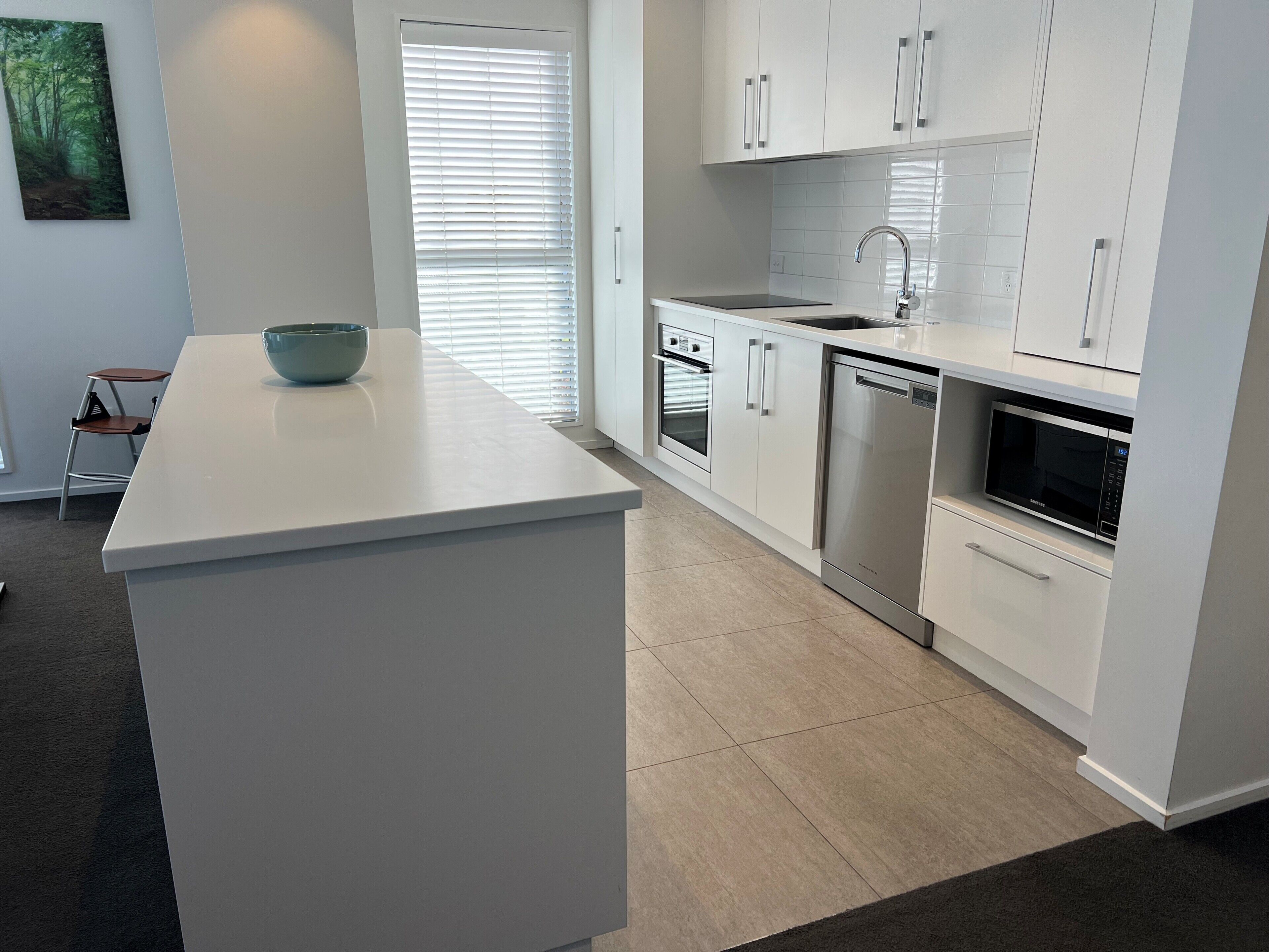 A modern kitchen with white cabinetry, a built-in oven, a dishwasher, and a microwave.