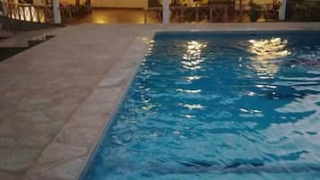 A swimming pool with a thatched roof structure in the background.