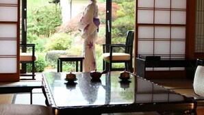 A traditional Japanese room with tatami flooring, a low table with tea sets, and sliding doors leading to a garden view. - Ryotei Takano (Chikuma)