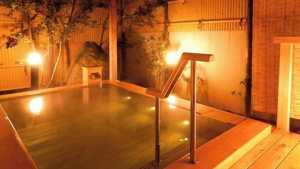 A hot spring bath area with wooden flooring, a wooden bench, and a bamboo wall. - Ryotei Takano (Chikuma)