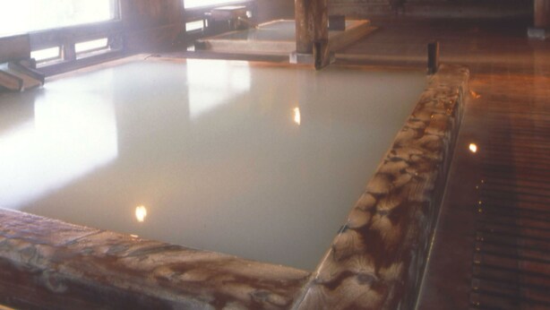 Un área de spa con un jacuzzi, vigas de madera y una pared de piedra.