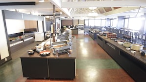 Una amplia cafetería con varios mostradores de servicio, un techo alto con vigas a la vista y una larga barra con diversas opciones de comida.