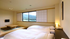 Habitación de hotel moderna con una cama grande, un escritorio pequeño, una ventana con vistas a las montañas y un teléfono junto a la cama.