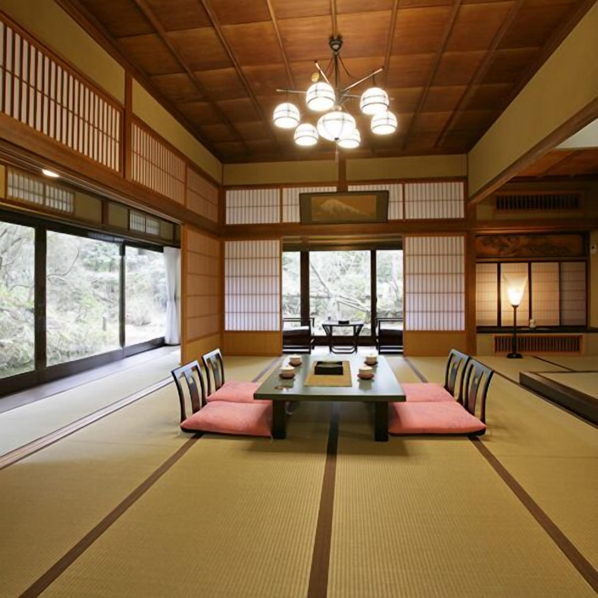 Una habitación japonesa tradicional con suelo de tatami, una mesa baja, cojines y puertas correderas.