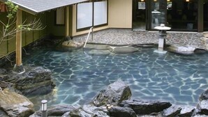 A clear pool with rocks, a stone pathway, and a building with a covered entrance. - Itsuura Kanko Hotel Daikanso (Kitaibaraki)