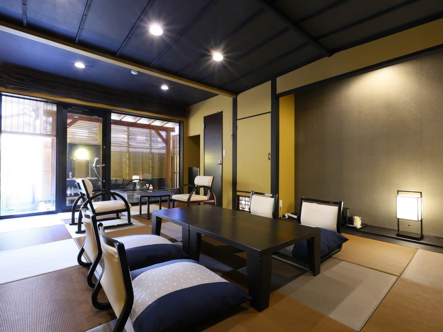 Un salón de conferencias con una larga mesa, sillas, esteras de tatami y un amplio ventanal.