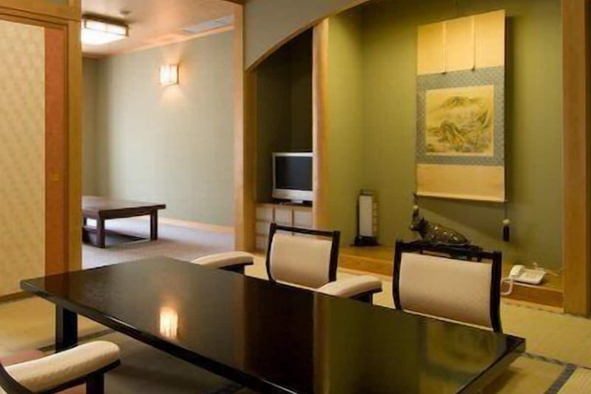 A conference room with a long table, chairs, a television, and a painting on the wall.