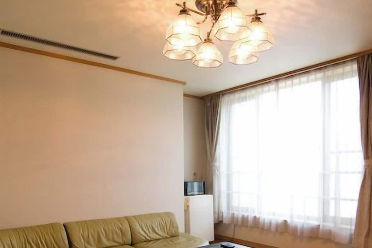 A living room with a sofa, a coffee table, and a window with curtains.