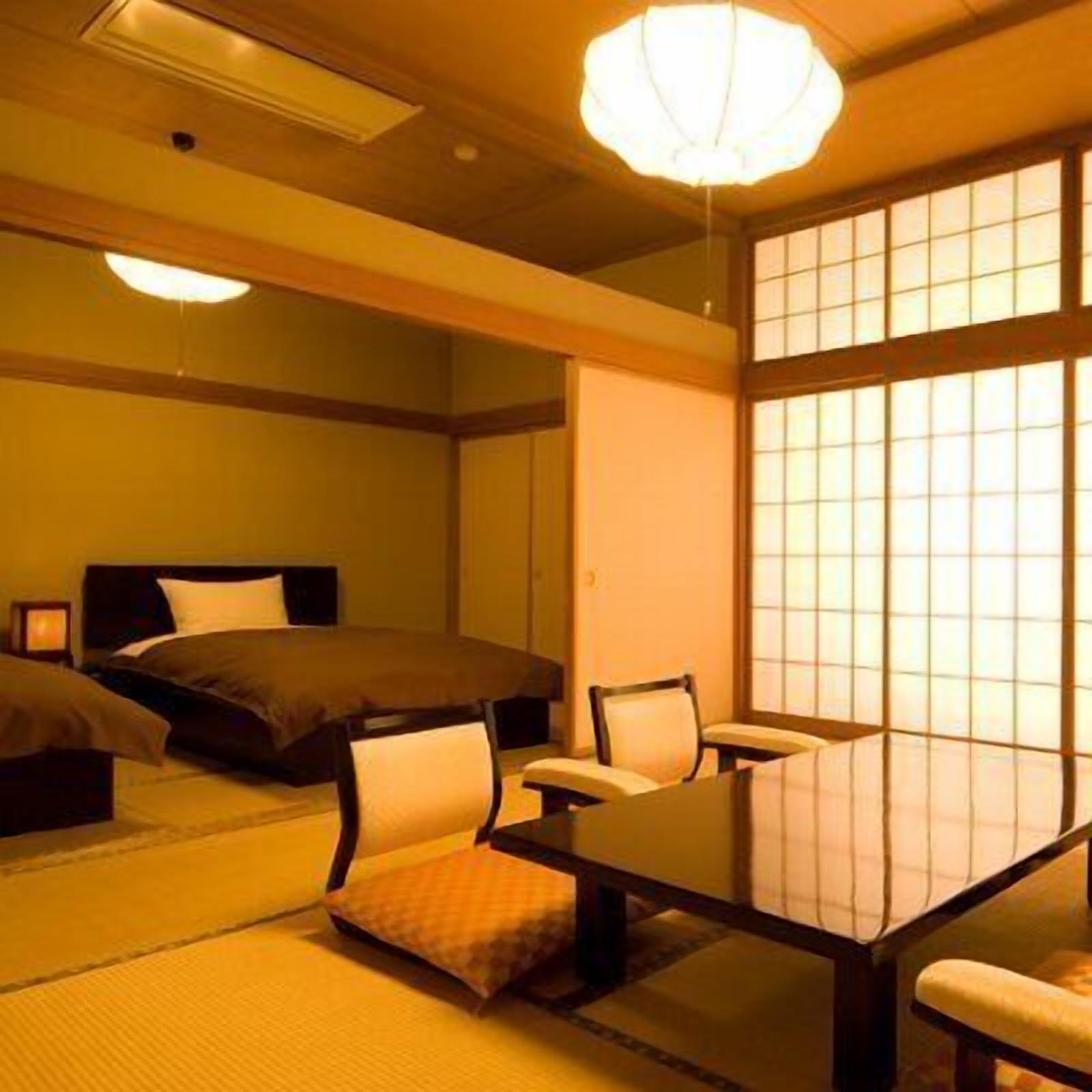 Una habitación tradicional japonesa con suelo de tatami, una mesa baja y una cama con cabecera oscura.