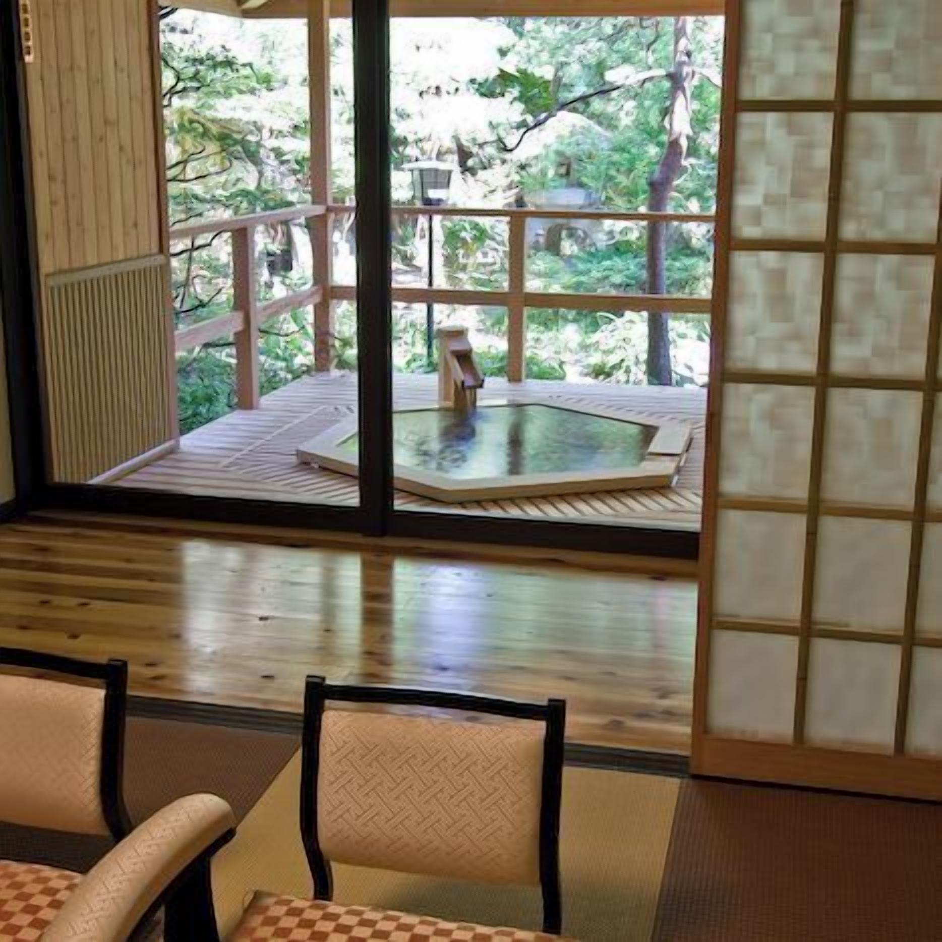 Una habitación con piso de madera, una zona de esteras de tatami, una mesa y sillas.