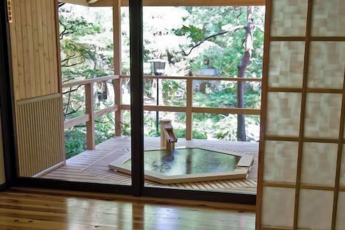 Una habitación con piso de madera, una zona de esteras de tatami, una mesa y sillas.