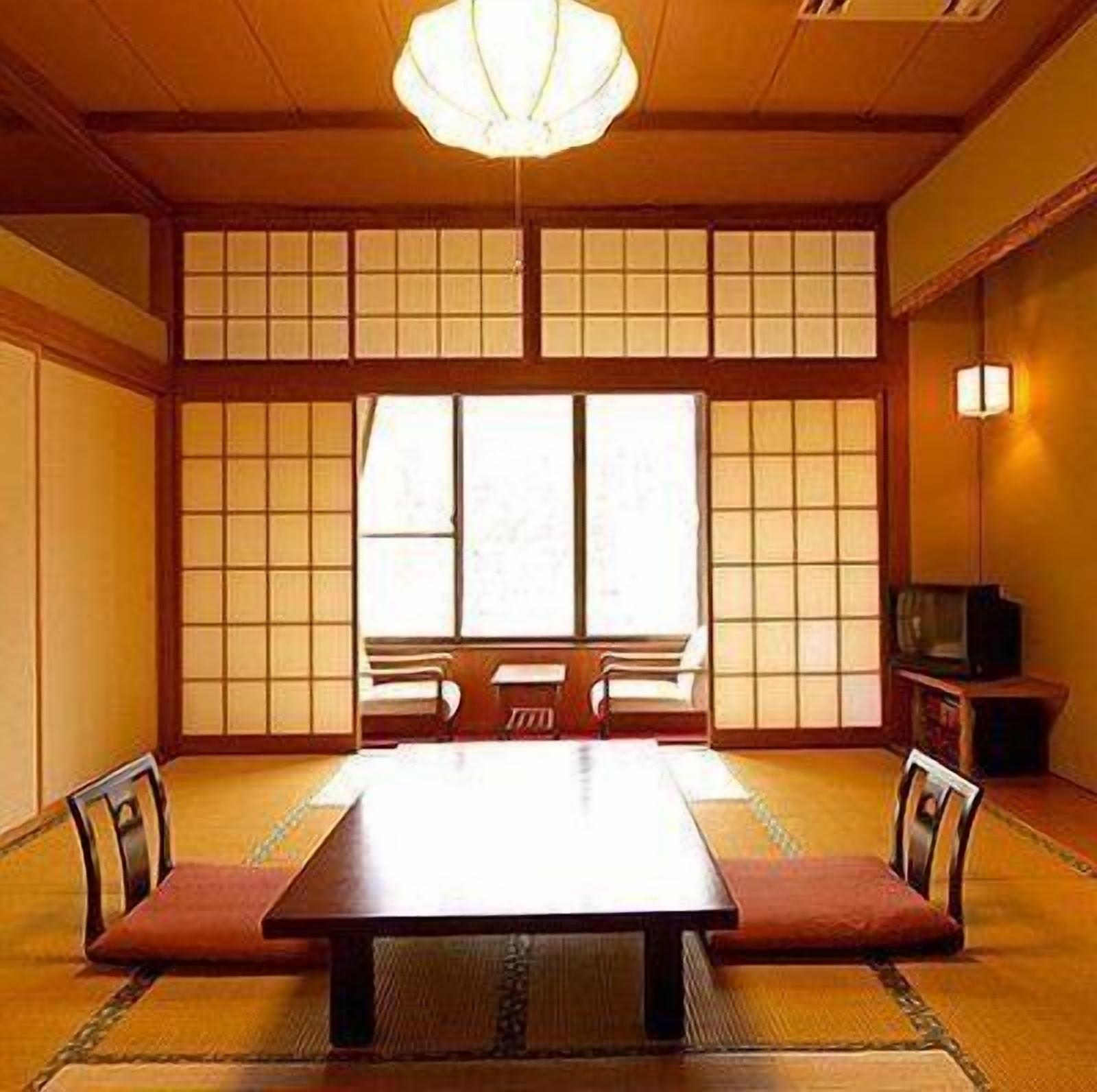 Una habitación japonesa tradicional con suelo de tatami, una mesa baja y puertas correderas.