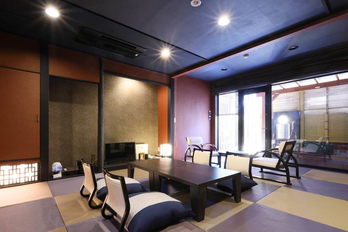 A conference room with tatami mats, a table, chairs, a television, and a large window.