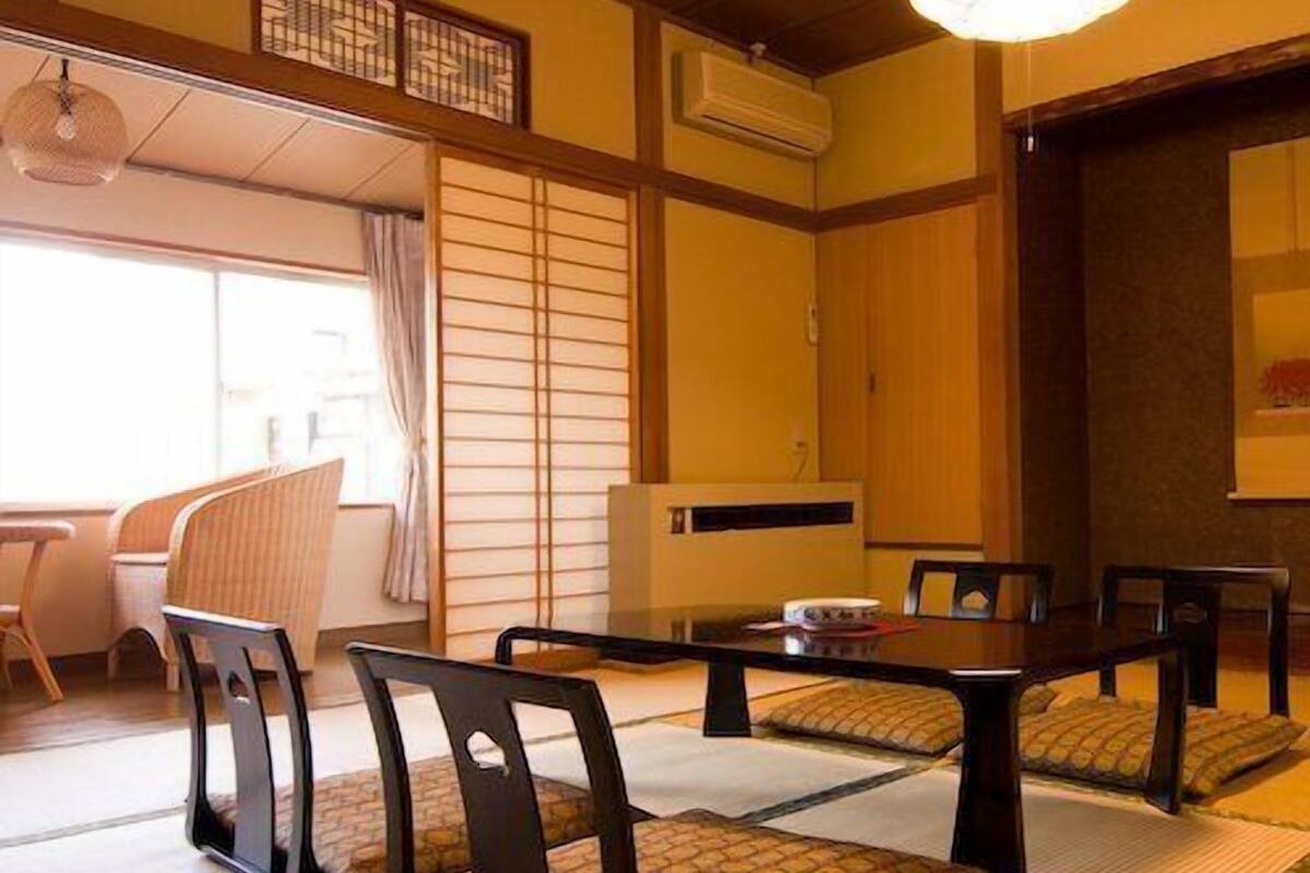 A traditional Japanese room with tatami flooring, a low table with chairs, and a sliding door.