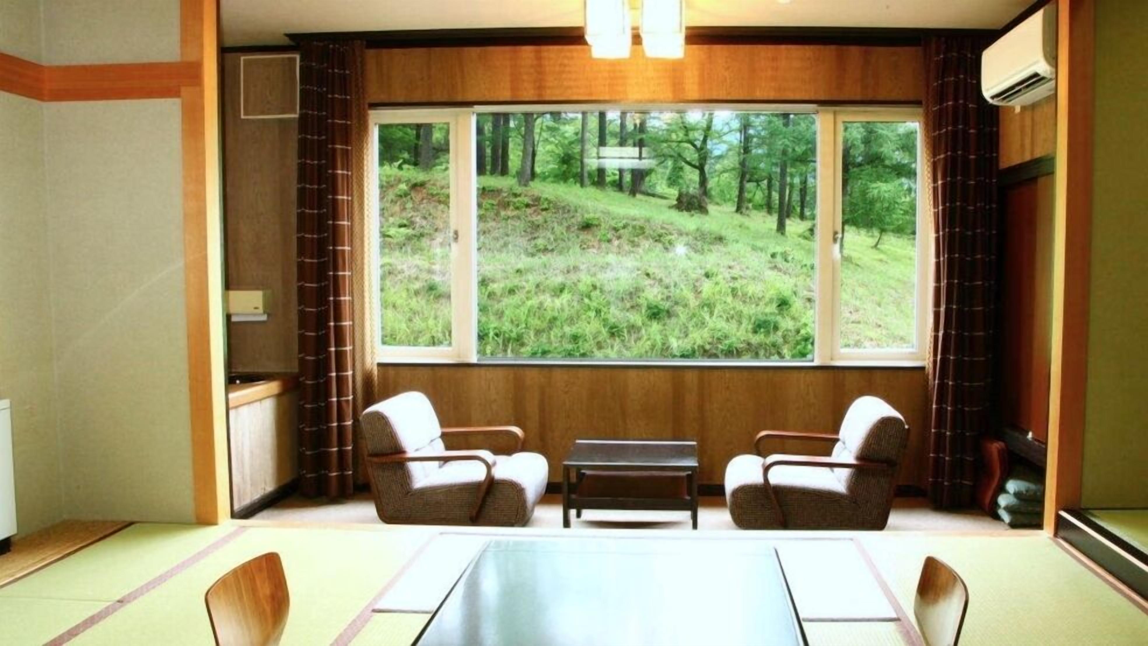 A room with a large window, two chairs, a small table, and a radiator.