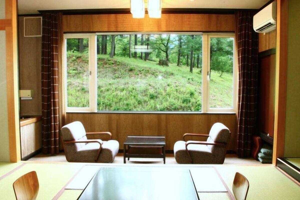 A room with a large window, two chairs, a small table, and a radiator.