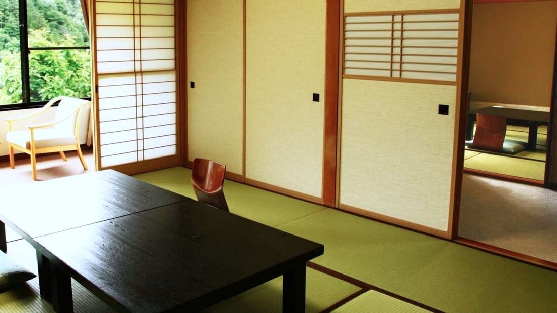 A traditional Japanese room with tatami flooring, a low table, and sliding doors.