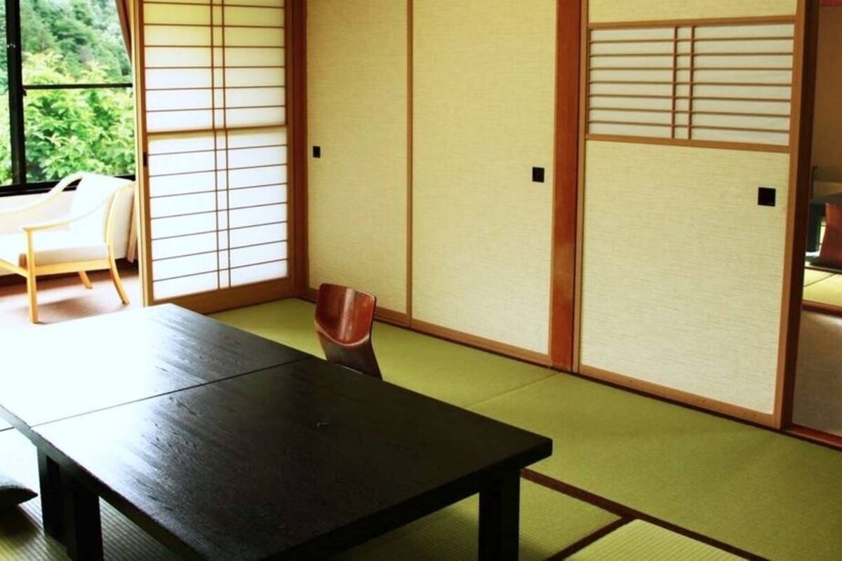 A traditional Japanese room with tatami flooring, a low table, and sliding doors.
