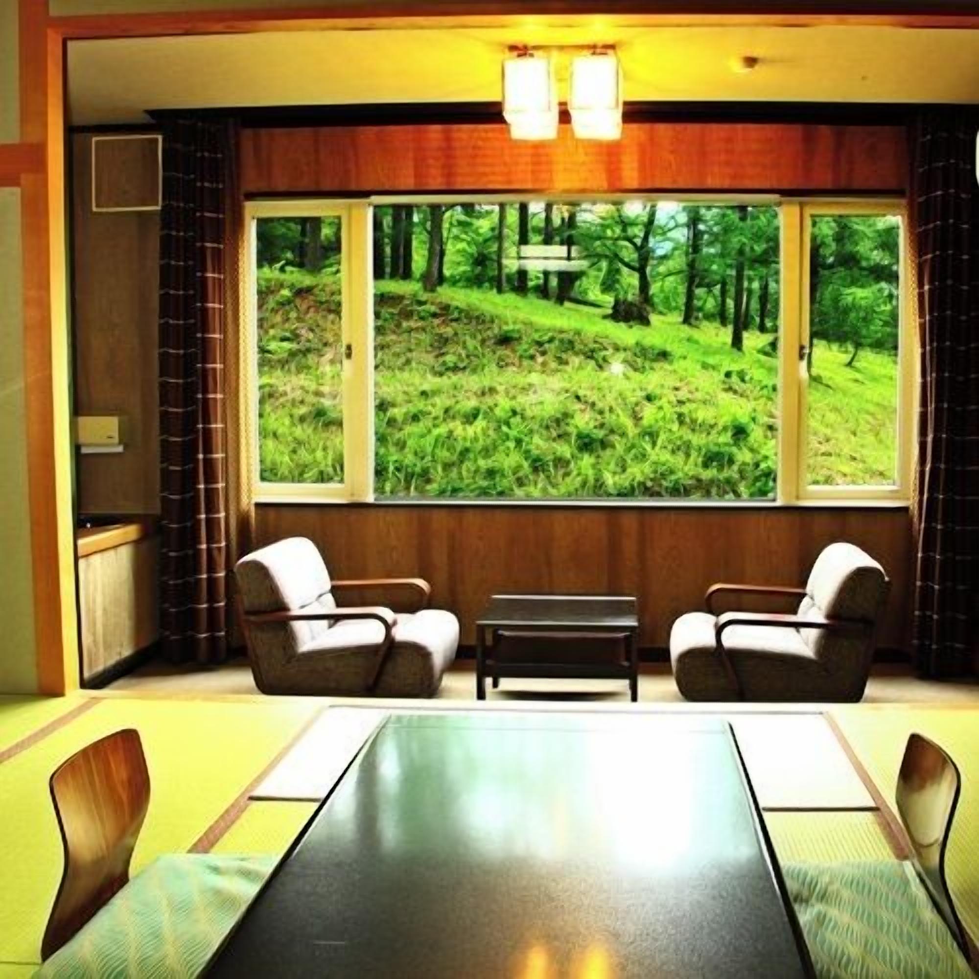 A conference room with a large window offering a view of a forested hillside.