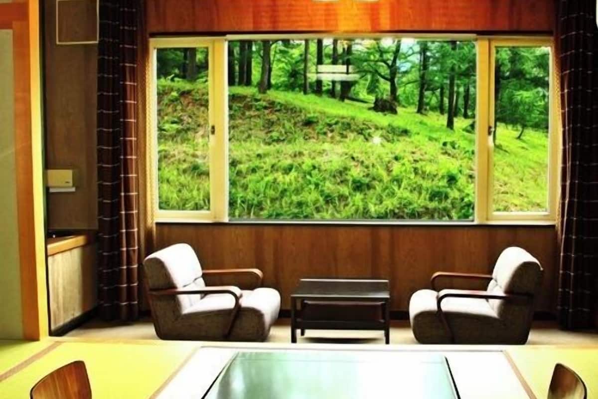 A conference room with a large window offering a view of a forested hillside.