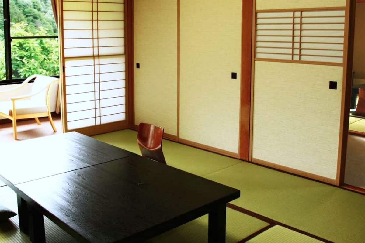 A traditional Japanese room with tatami flooring, a low table, and sliding doors.