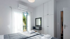 Un dormitorio con dos camas, un equipo de aire acondicionado, un espejo y una puerta que da a otra habitación.