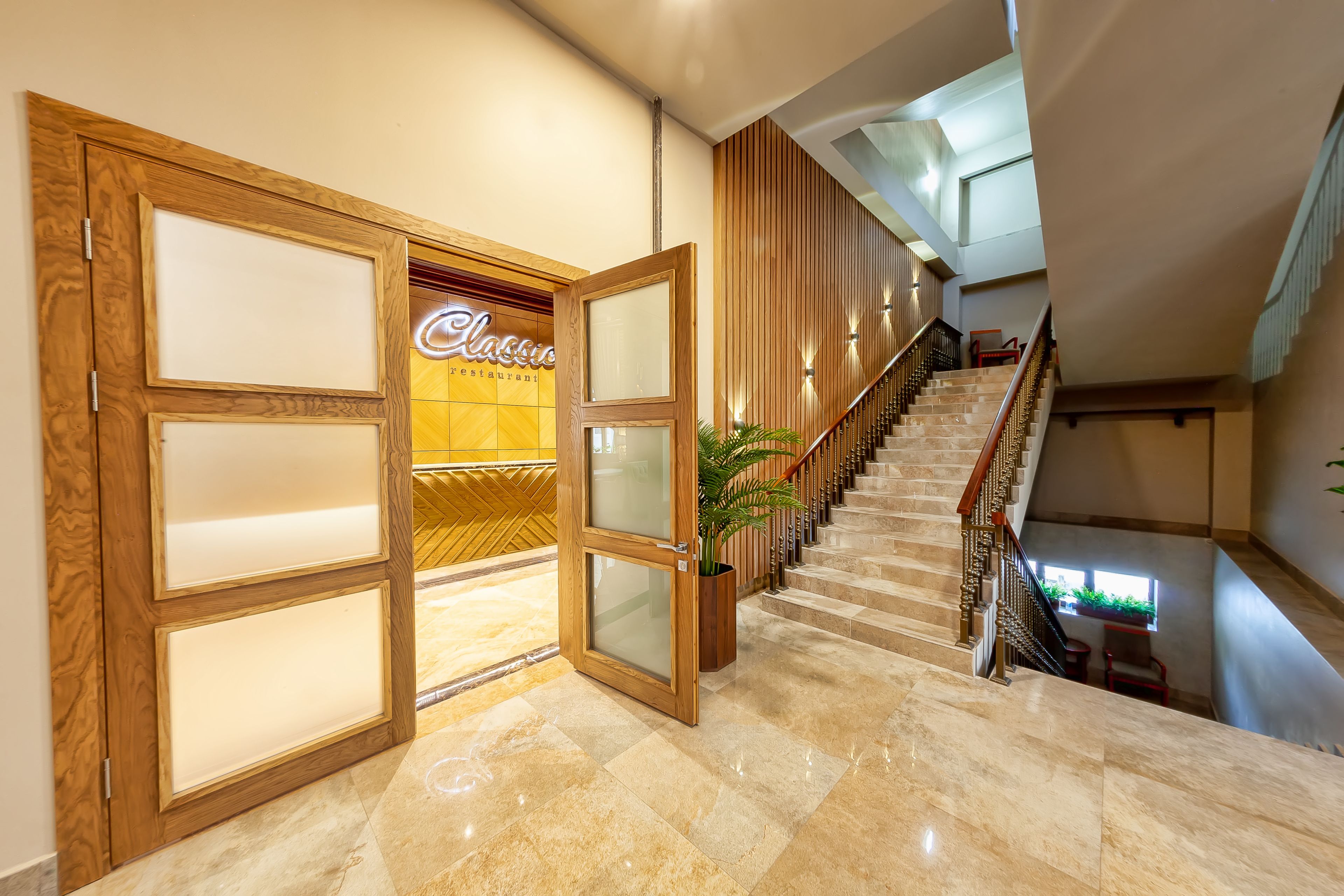 A hotel entrance with a wooden door, a staircase, and a sign for 'Classic Restaurant'.