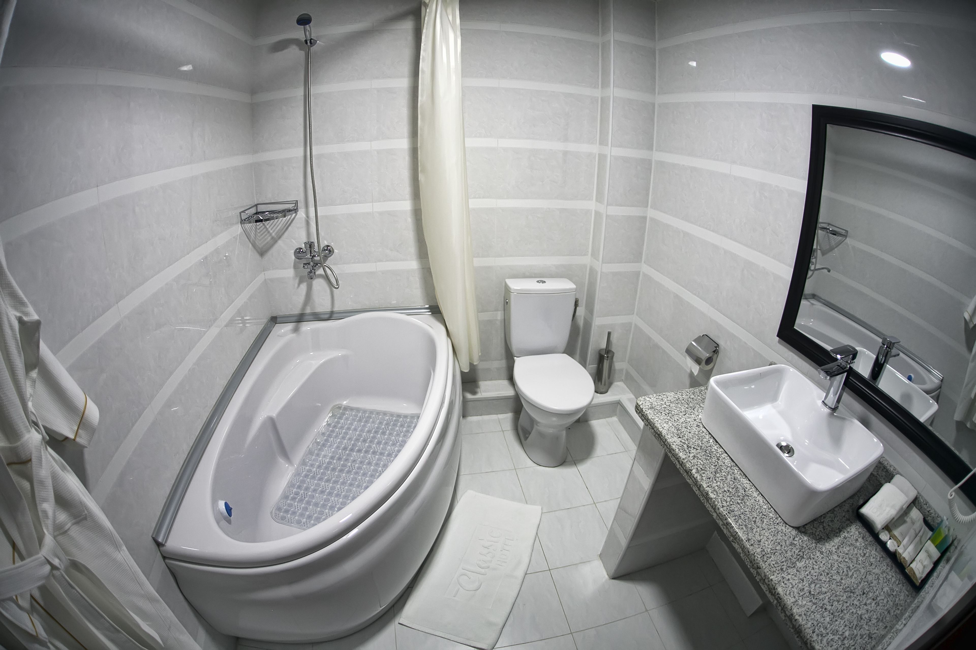 A modern bathroom with a freestanding bathtub, a toilet, and a sink with a mirror.