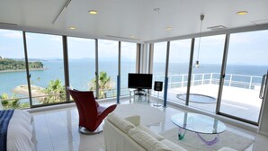 Sala de estar moderna com uma grande janela de vidro que dá para um corpo de água e uma costa distante.