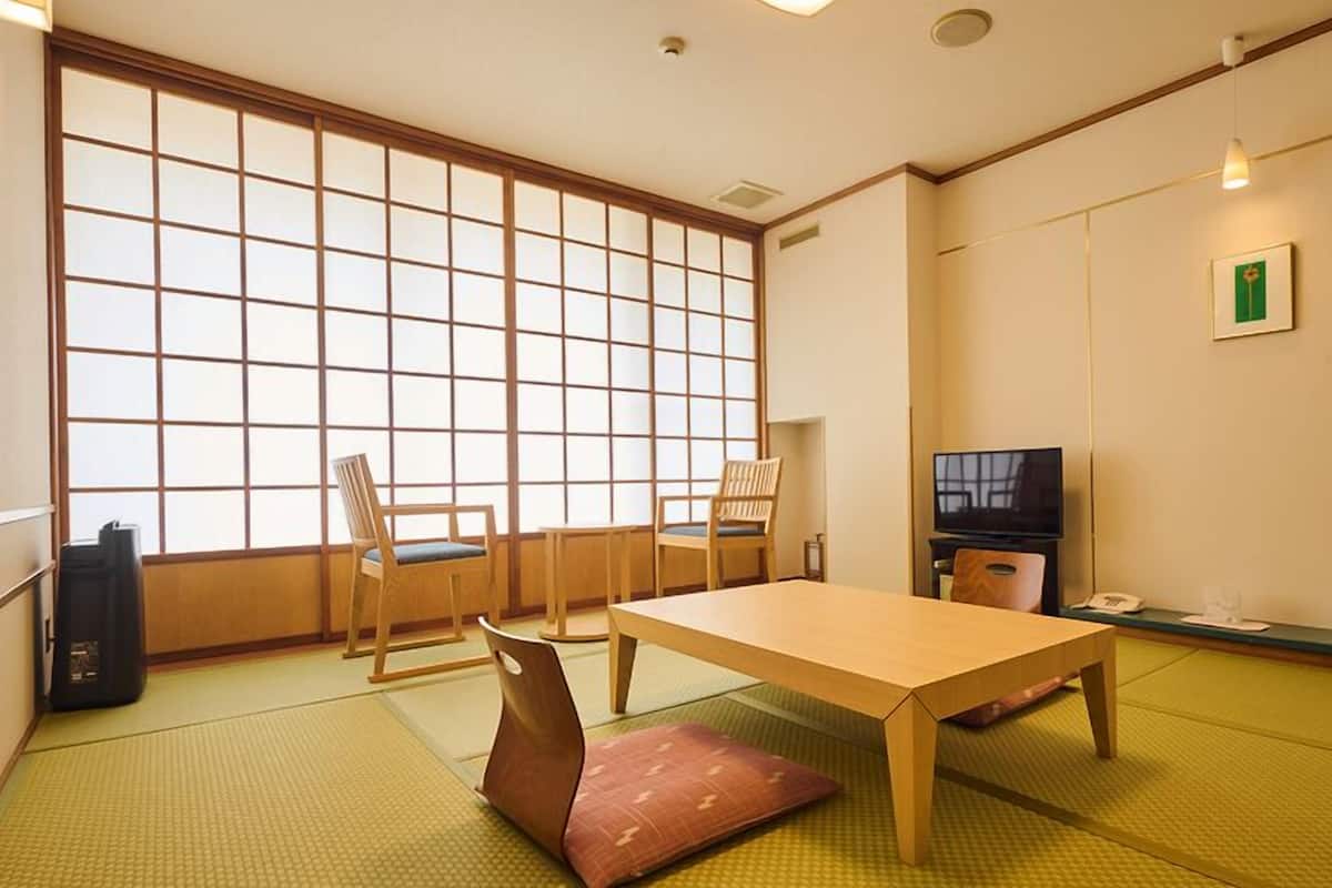 Perinteinen japanilainen huone, jossa on tatamimatto, matala pöytä, puiset tuolit, televisio ja liukuovi.