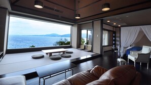 Quarto de hotel moderno com uma grande janela que oferece vista para o mar.