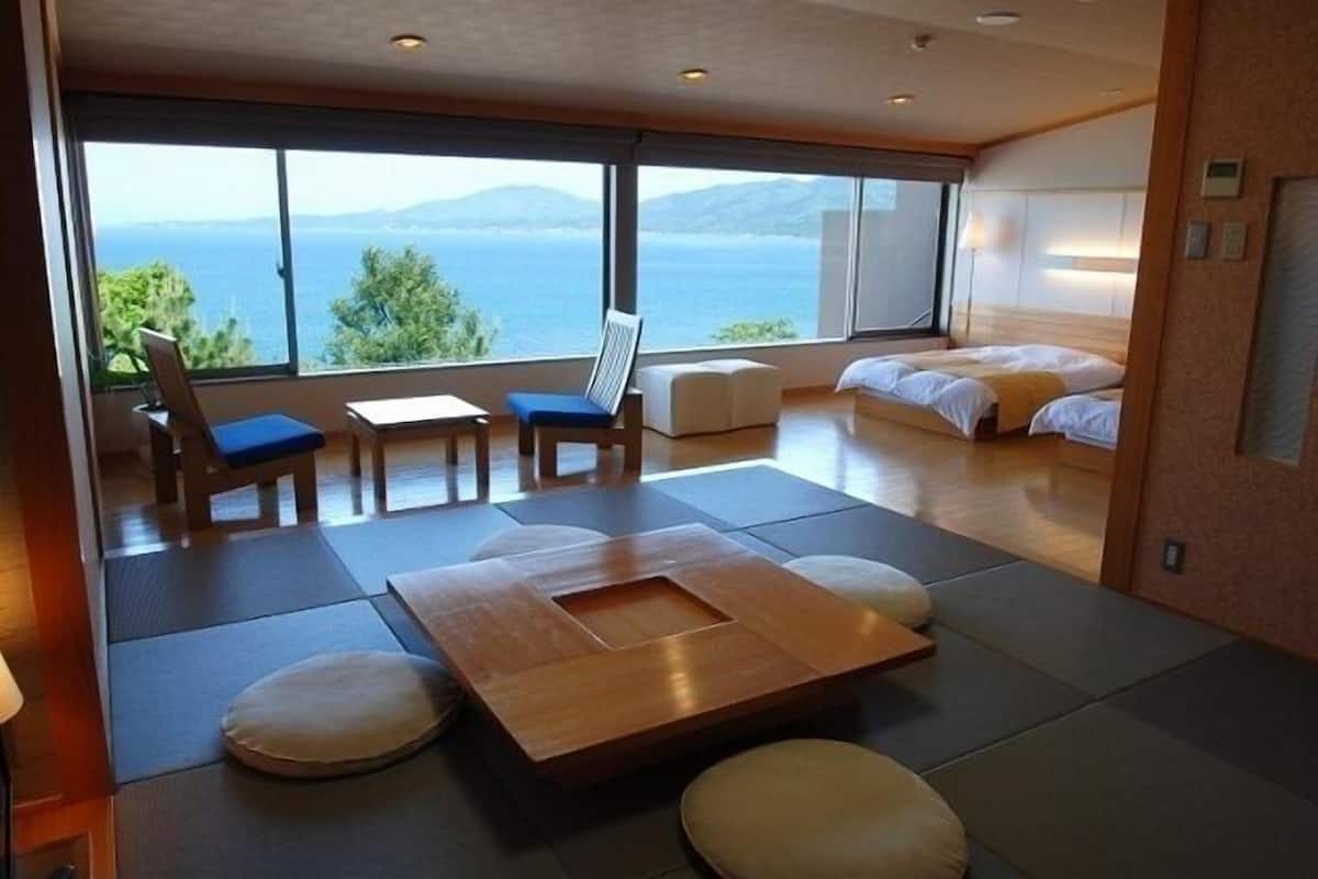 Une chambre d’hôtel moderne avec une grande fenêtre, une table basse en bois, un canapé et un lit.