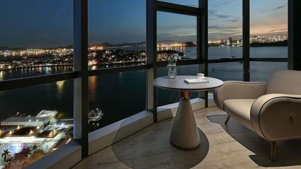 Una habitación moderna con un amplio ventanal panorámico, una mesa redonda y un sofá.