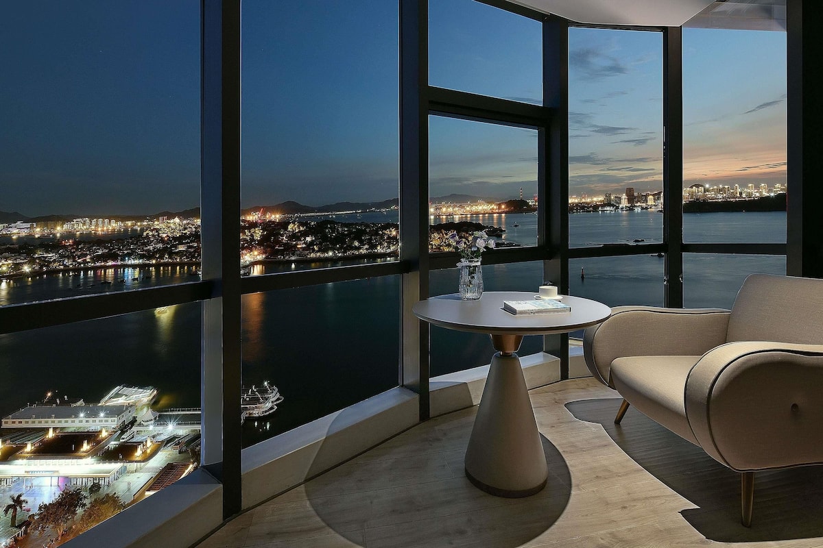 Une pièce moderne dotée d’une grande fenêtre panoramique, d’une table ronde et d’un canapé.
