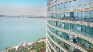 Un edificio alto con varios pisos, amplias ventanas y vista a un cuerpo de agua.
