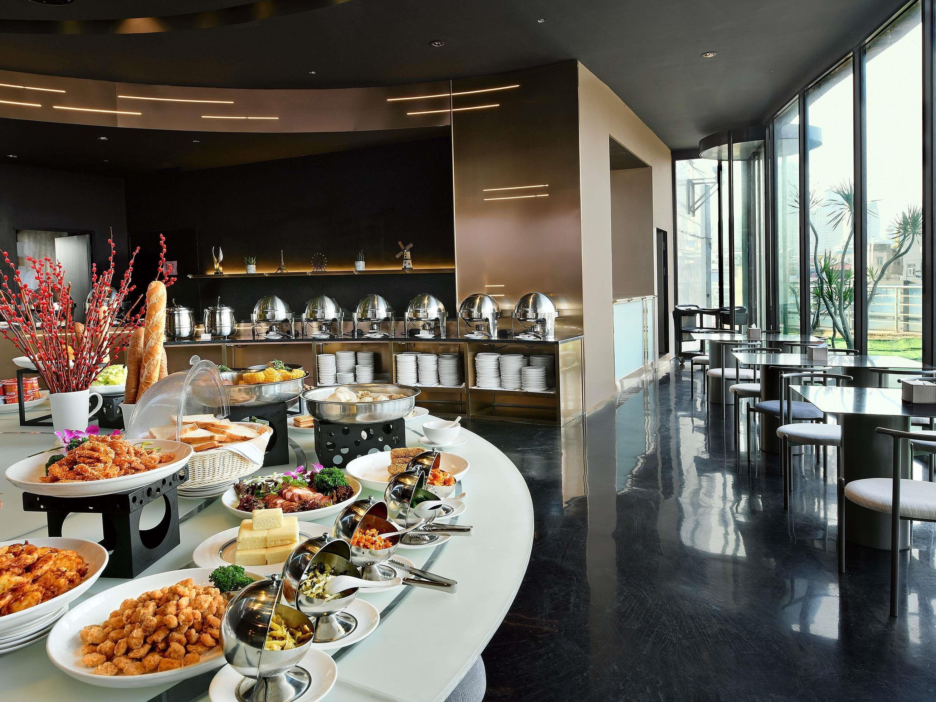 Un buffet proposant une variété de plats, un intérieur moderne et de grandes fenêtres.