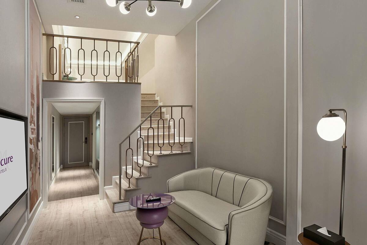 L’intérieur moderne d’un hôtel, avec un escalier, un canapé, une petite table ronde et un lampadaire.