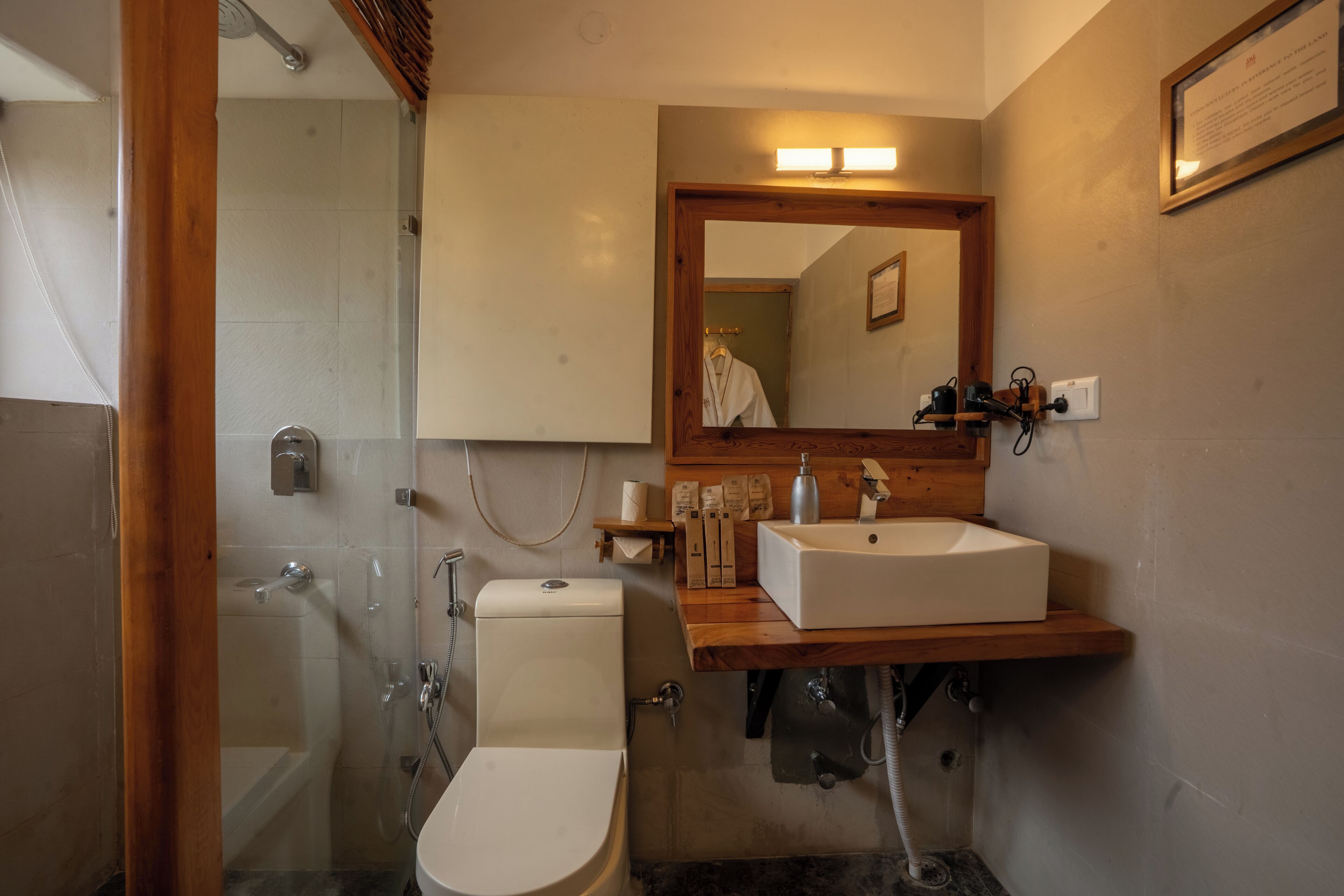 A bathroom with a glass shower enclosure, a toilet, a sink with a wooden countertop, and a mirror above the sink.