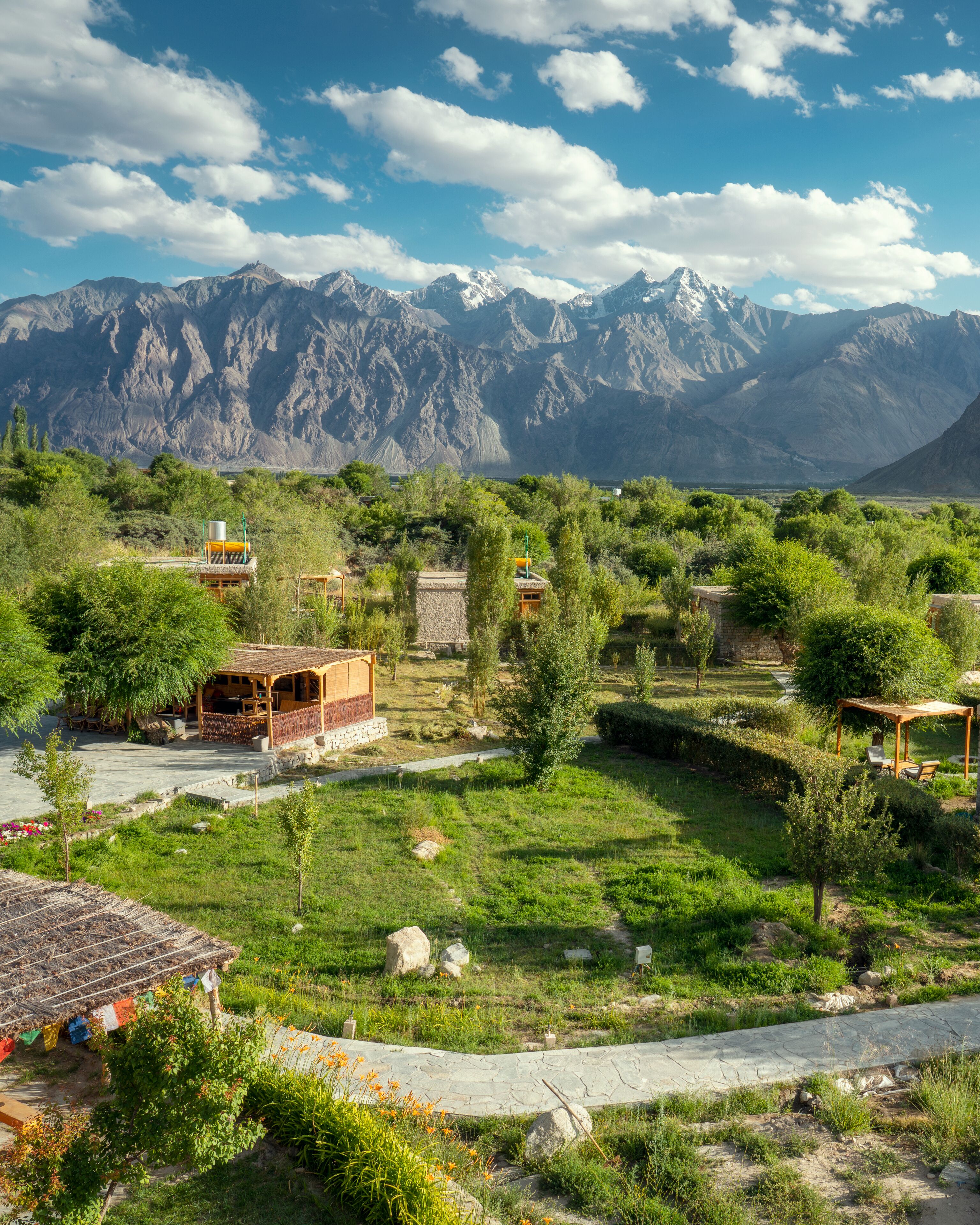 A rural village with traditional houses, a paved road, and mountains in the background.