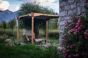 Una pérgola de madera con dos sillones de descanso en un jardín.