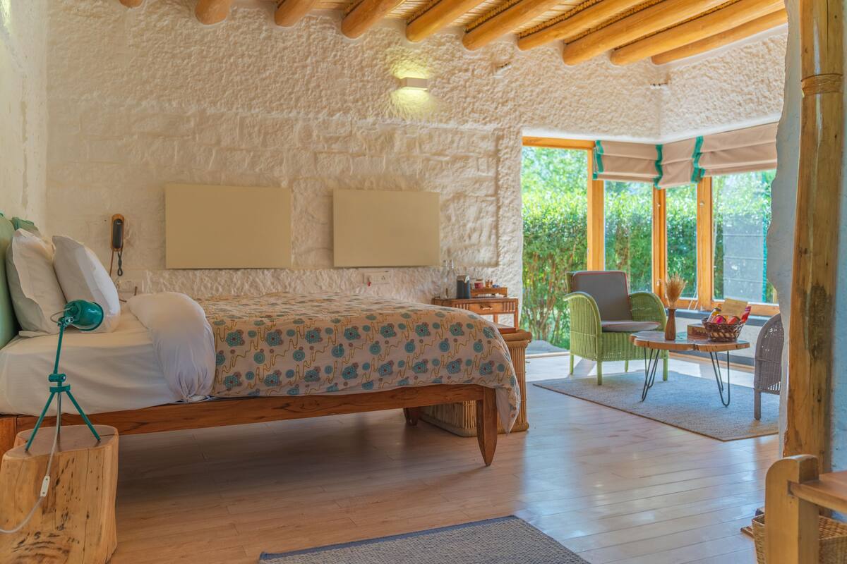 Un dormitorio con cama de madera, una mesita, una silla y vistas al exterior.