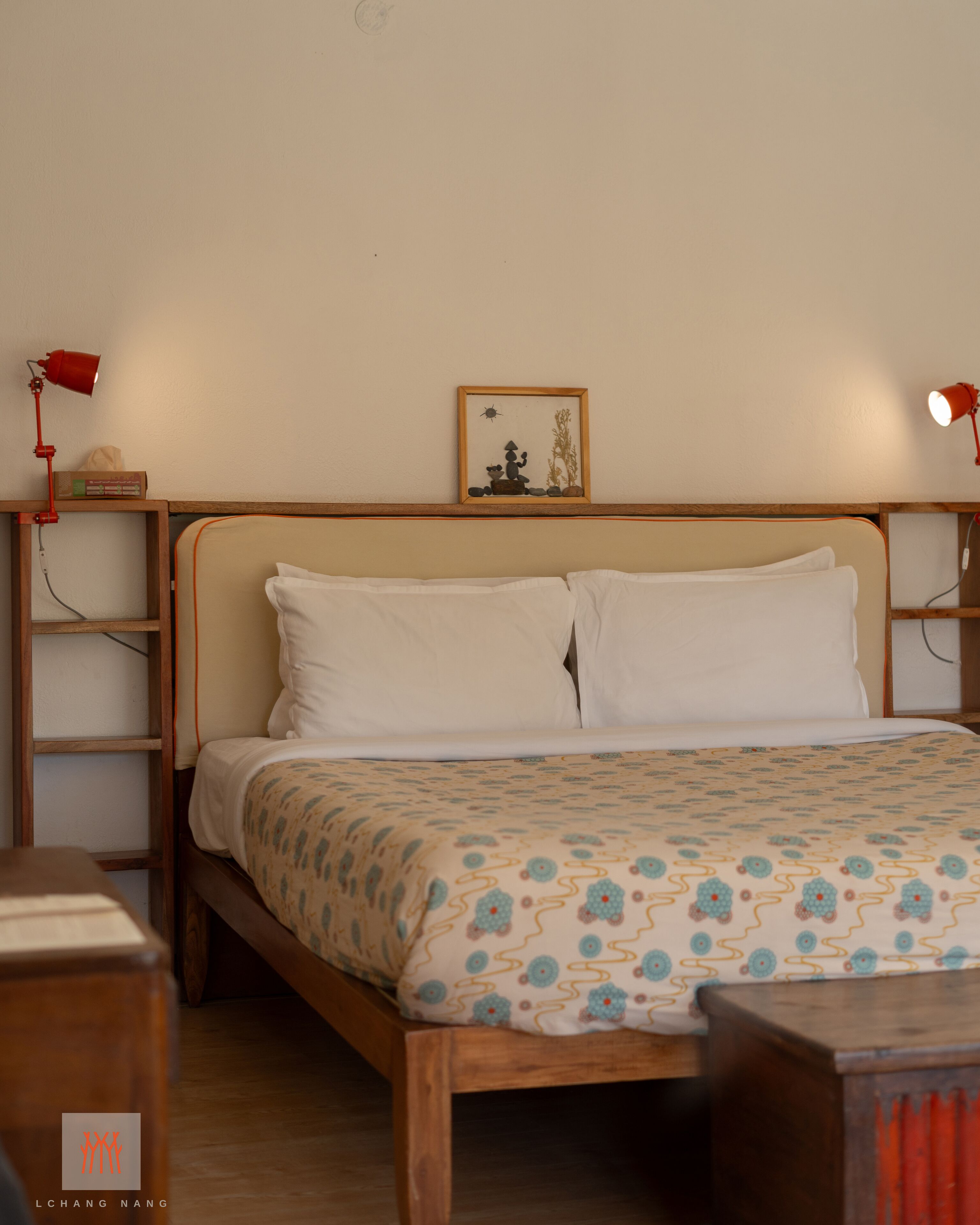 A neatly made bed with a patterned bedspread, a wooden headboard, and two bedside lamps.