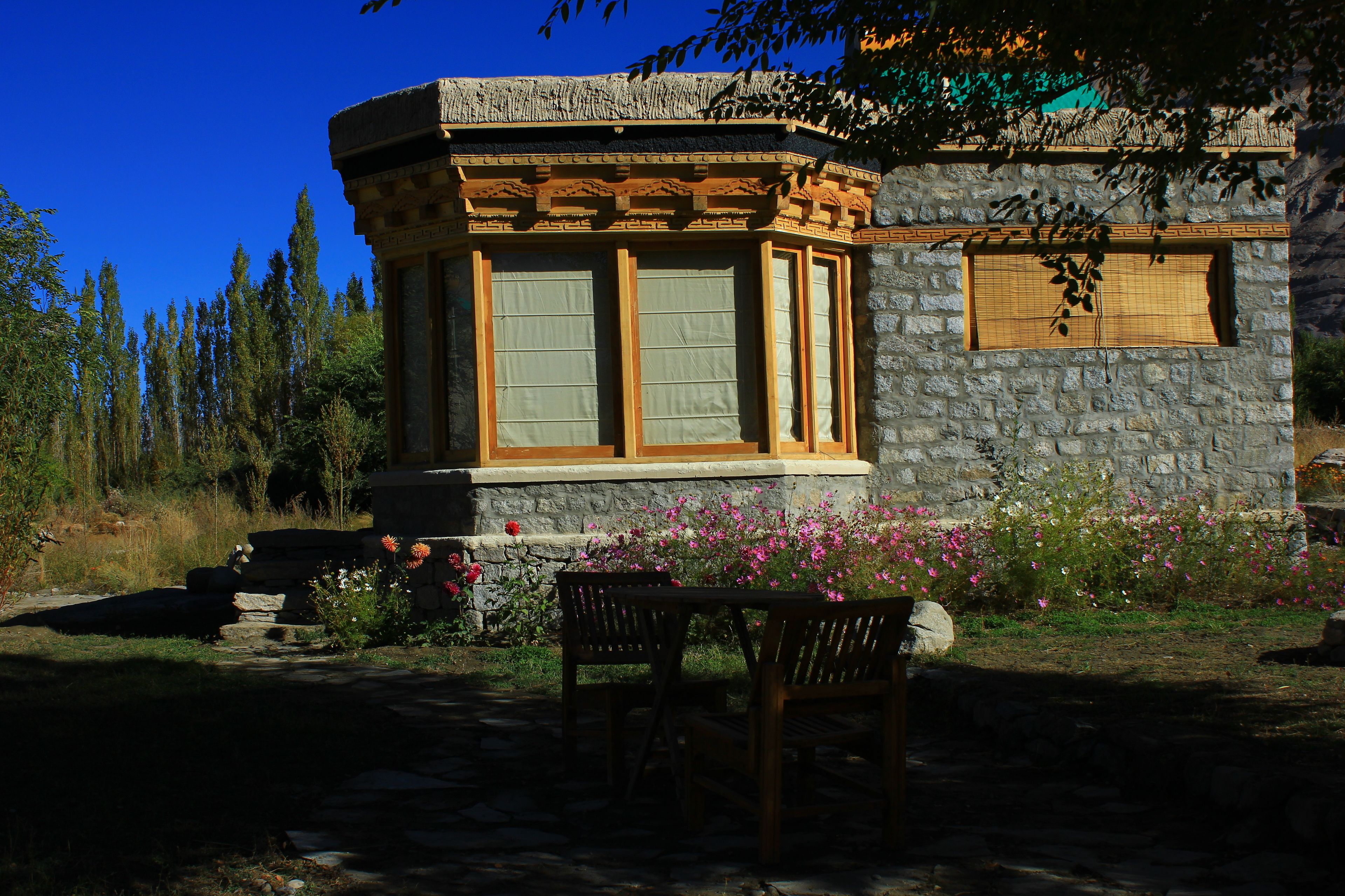 A stone building with a window and a small table with chairs in front.