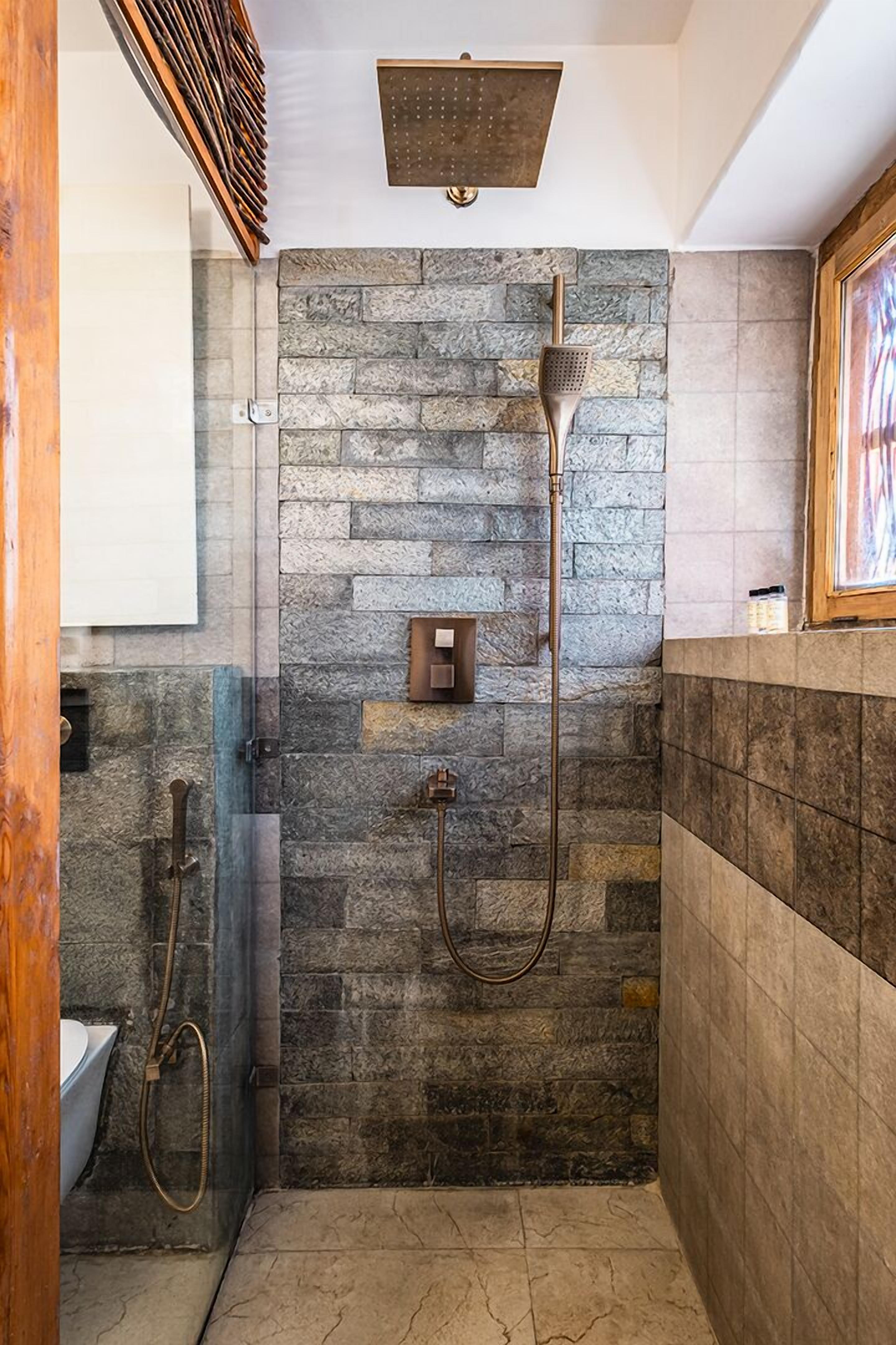 A modern bathroom with a stone wall, a shower, and a toilet.