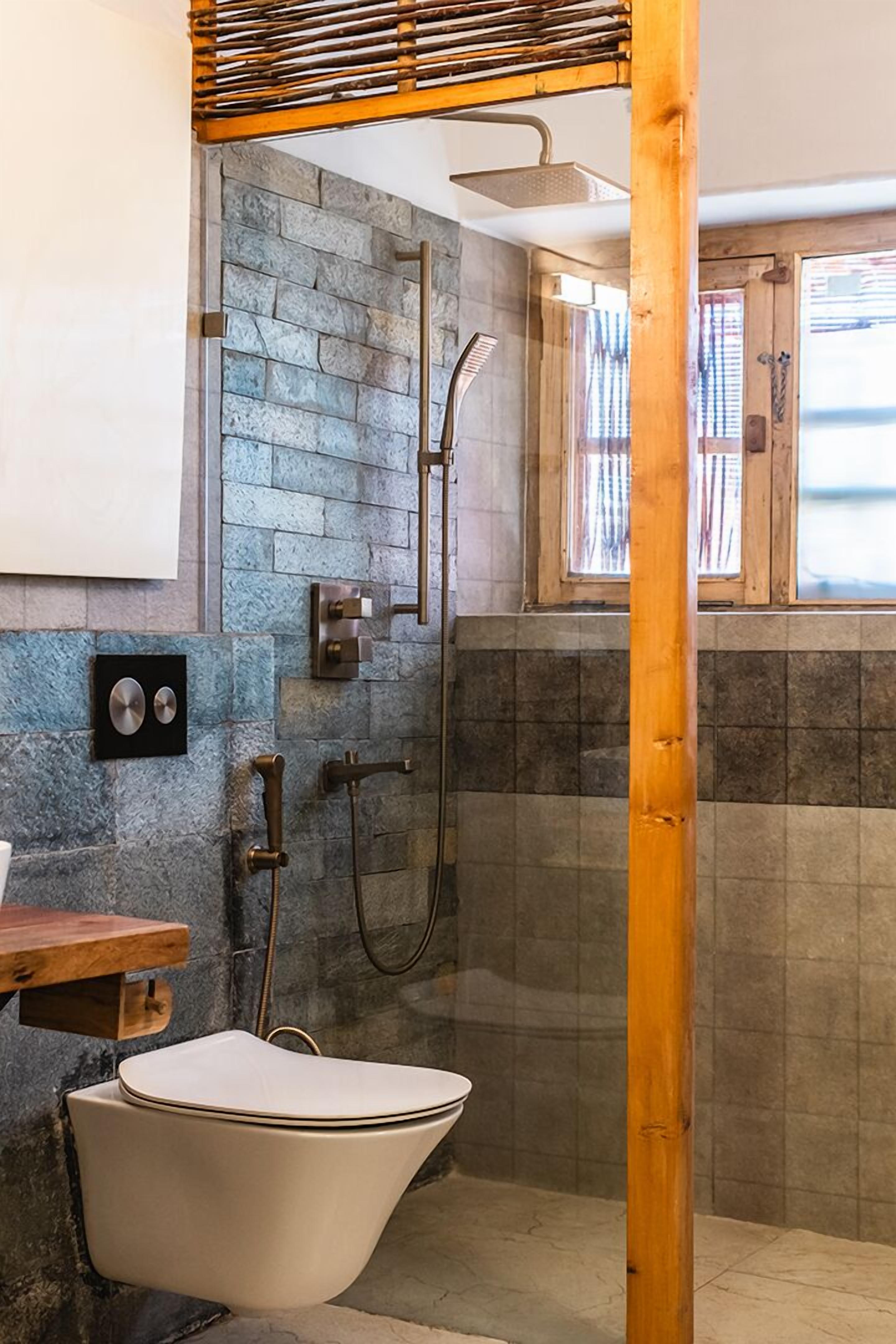 Un baño con una bañera de patas de león, ducha y pared de piedra.