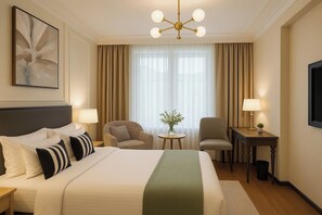 A hotel room with a large bed, two armchairs, a small table with a lamp, a vase with flowers, and a painting on the wall. - Aauris (Kolkata)