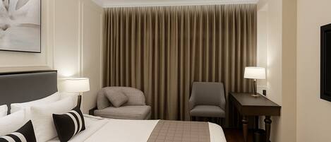 A hotel room with a bed, two chairs, a desk, and a ceiling fan.