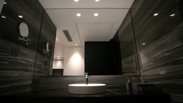 Un baño moderno con un lavamanos redondo, paredes espejadas e iluminación empotrada en el techo.