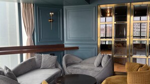 A modern lounge area with a blue wall, a round table, and two yellow armchairs. - Aauris (Kolkata)