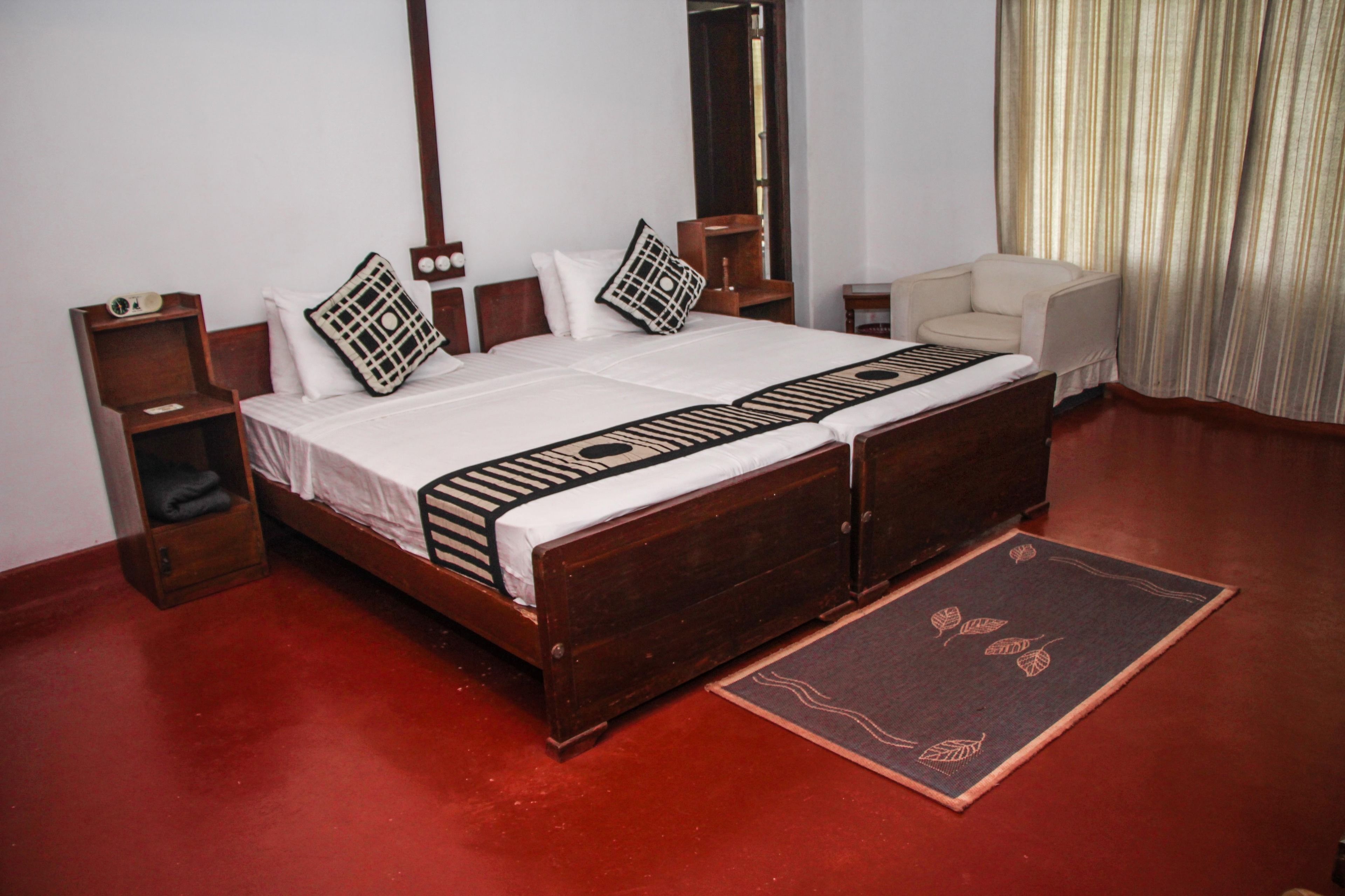 A double bed with a wooden frame, a bedside table, a chair, and a red carpet.